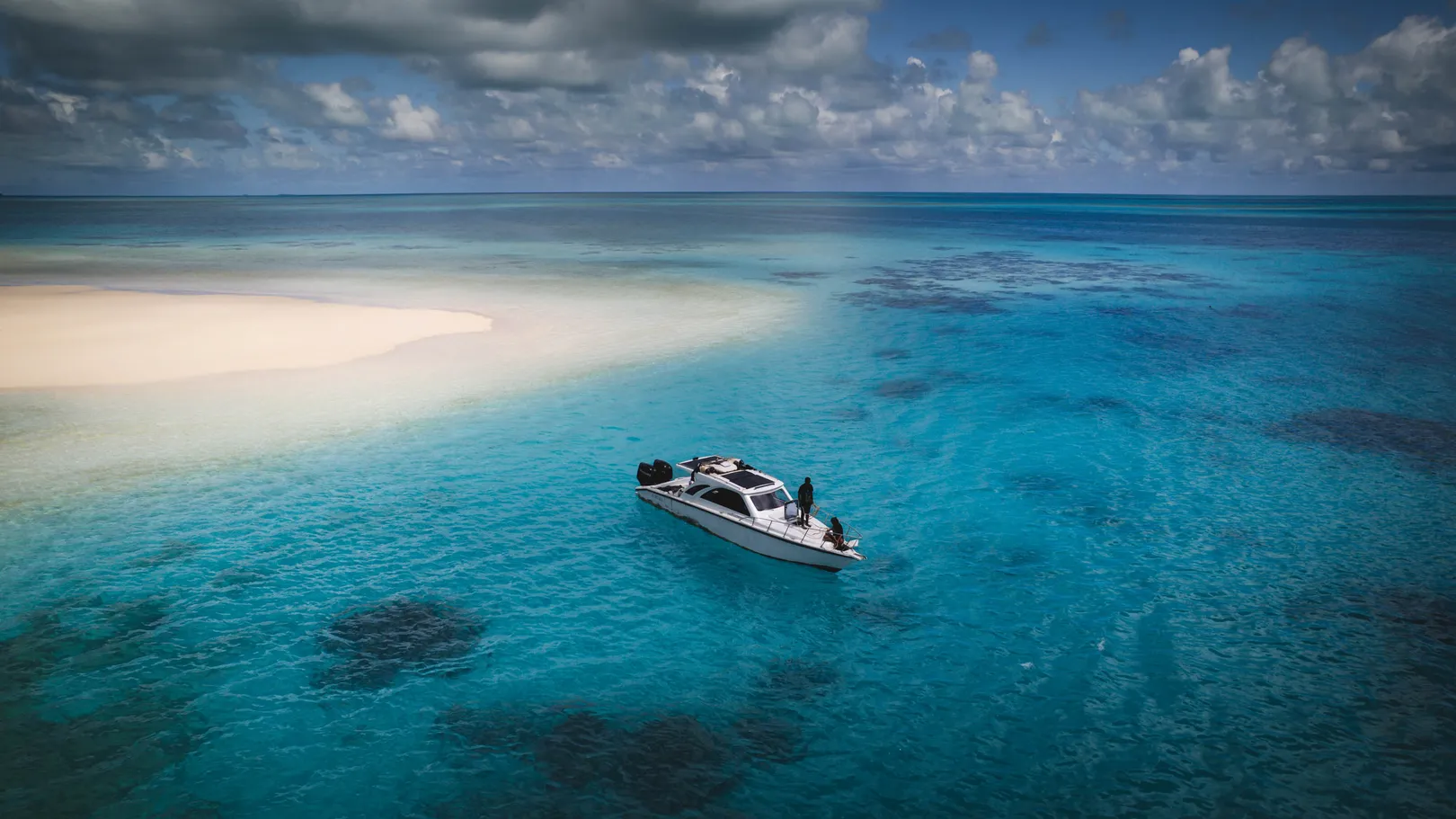 Boat anchored beside a brilliant white sandbank in Ayau, Raja Ampat